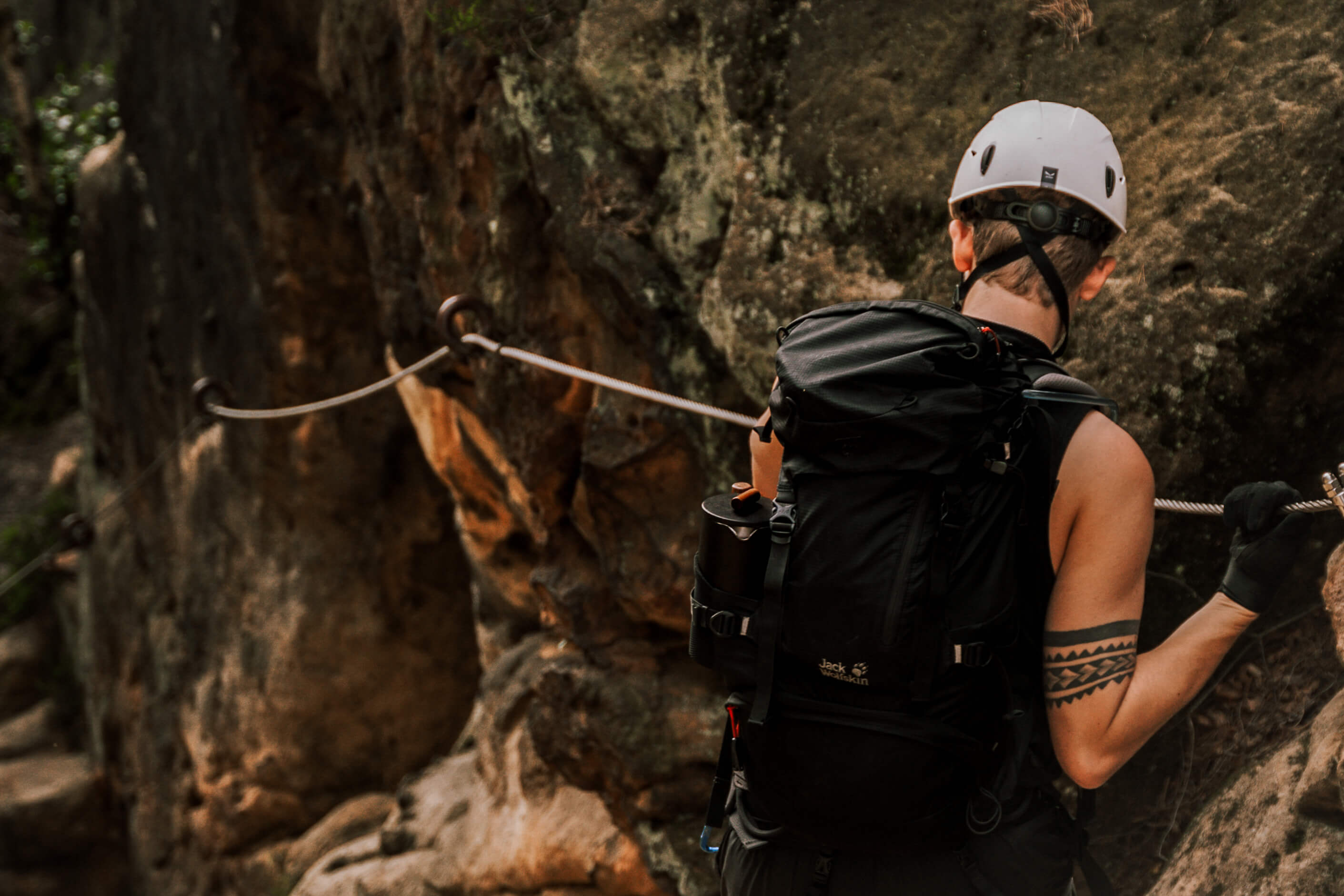 Person mit Rucksack und Kaffeezubehör unterwegs auf einem Klettersteig in den Bergen